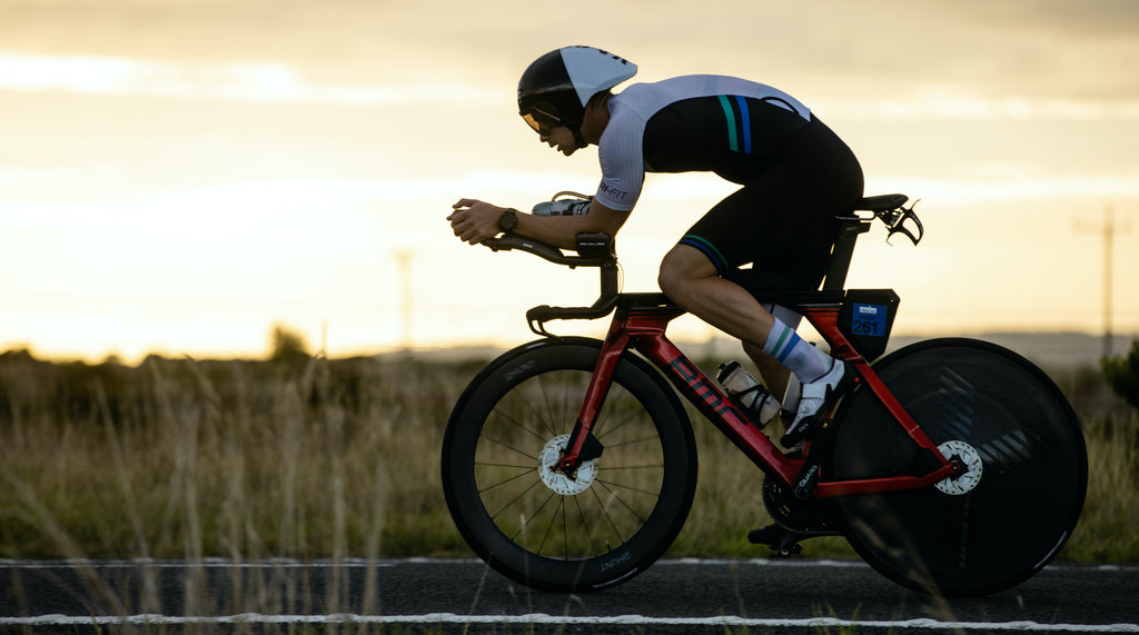 man cycling across the road with sunset in the background, wearing the evo tri suit